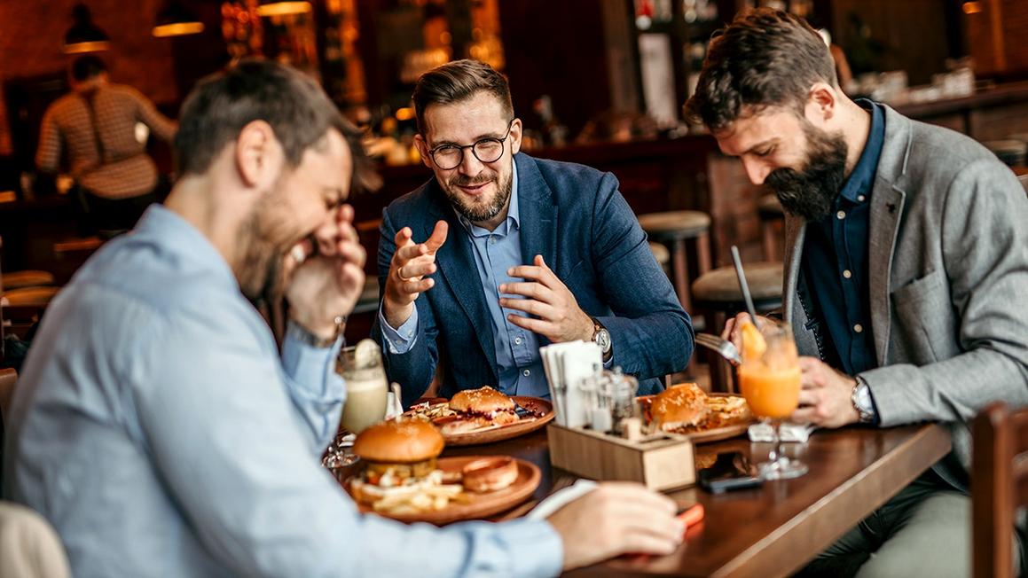 group of guys eating burgers at restaurant