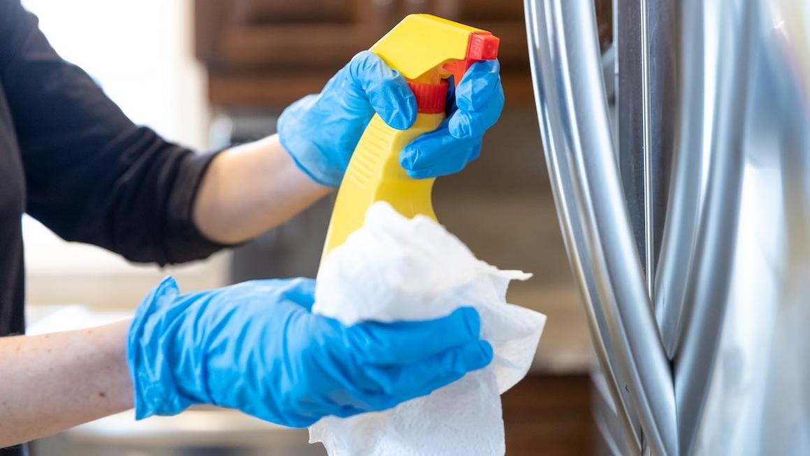 woman cleaning stainless steel fridge