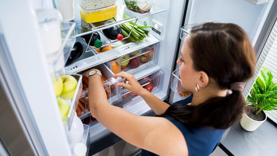 Ngủ Ngon Hơn Nhờ Thay Đổi Chế Độ Ăn Uống? 1 woman reaches into produce drawer in refrigerator