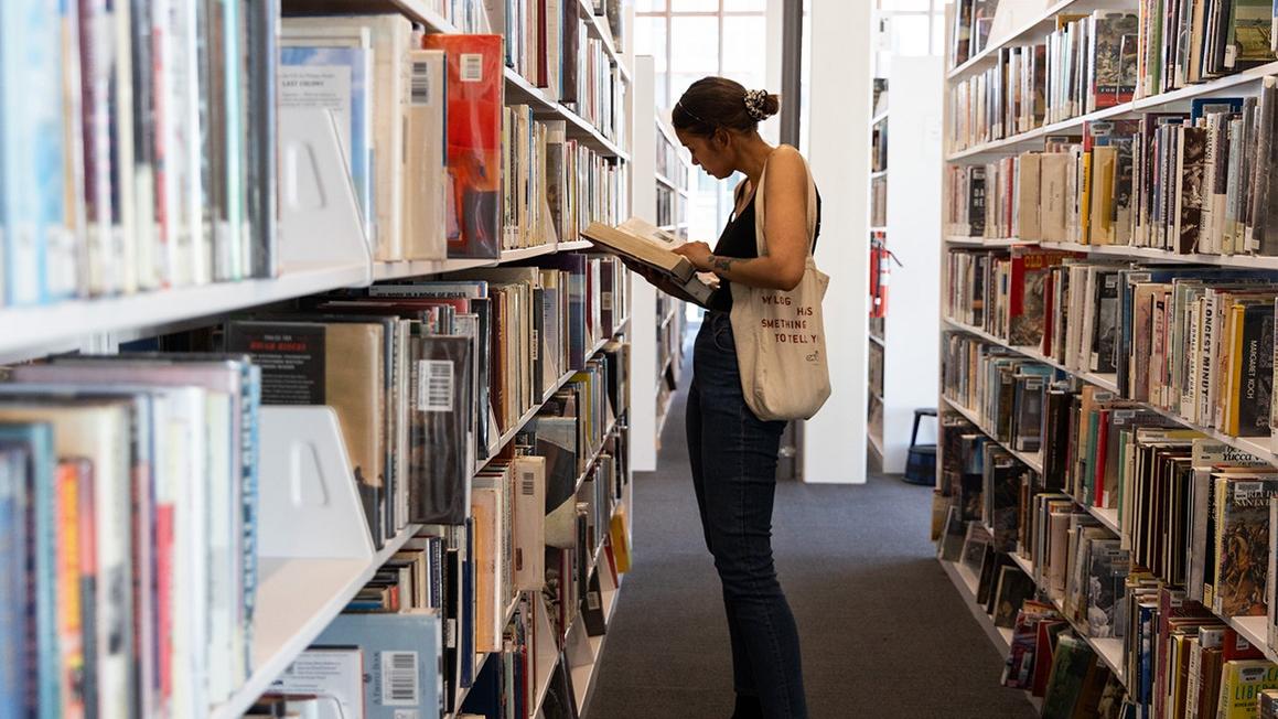 person at library shelves