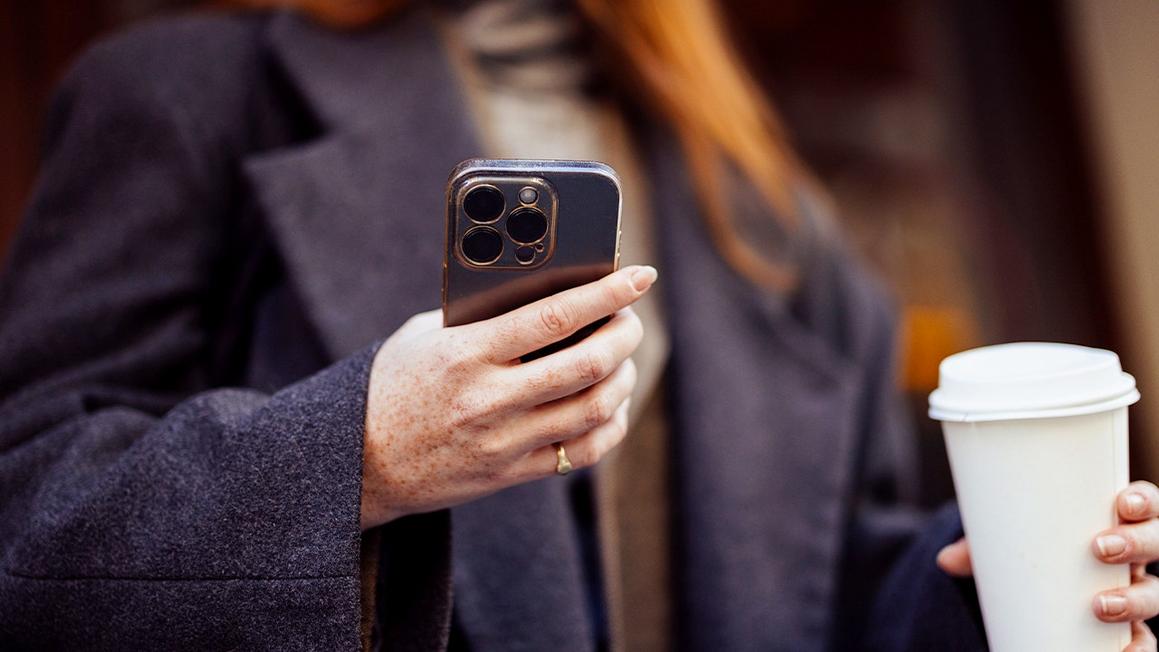 woman holds coffee phone