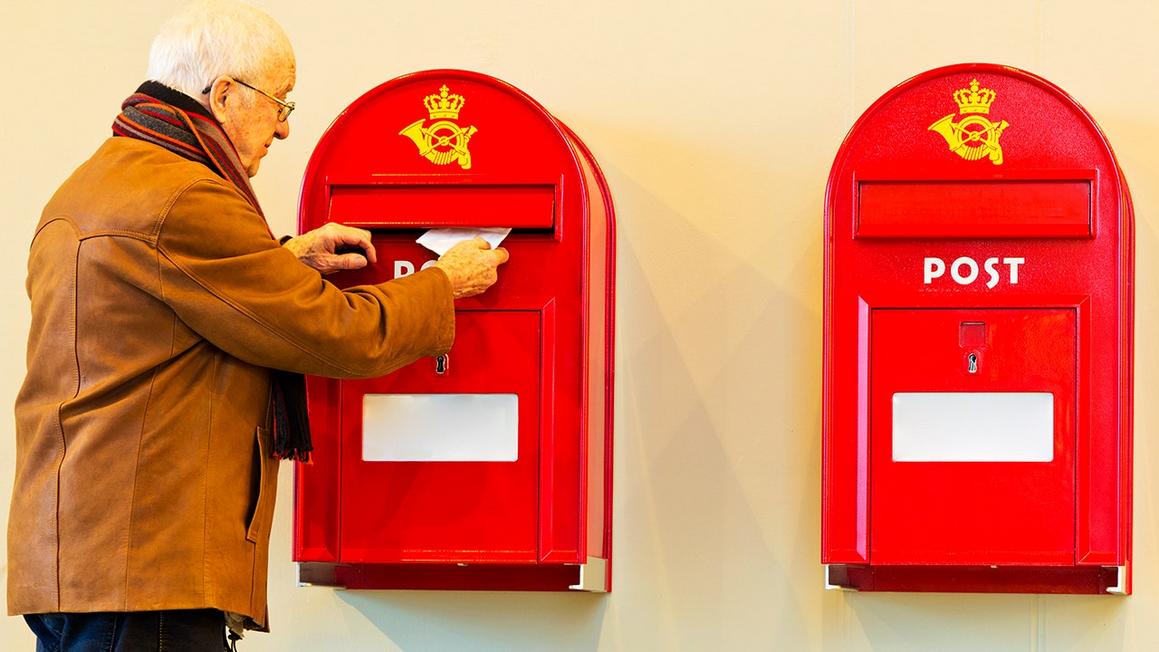elderly man puts letter in danish