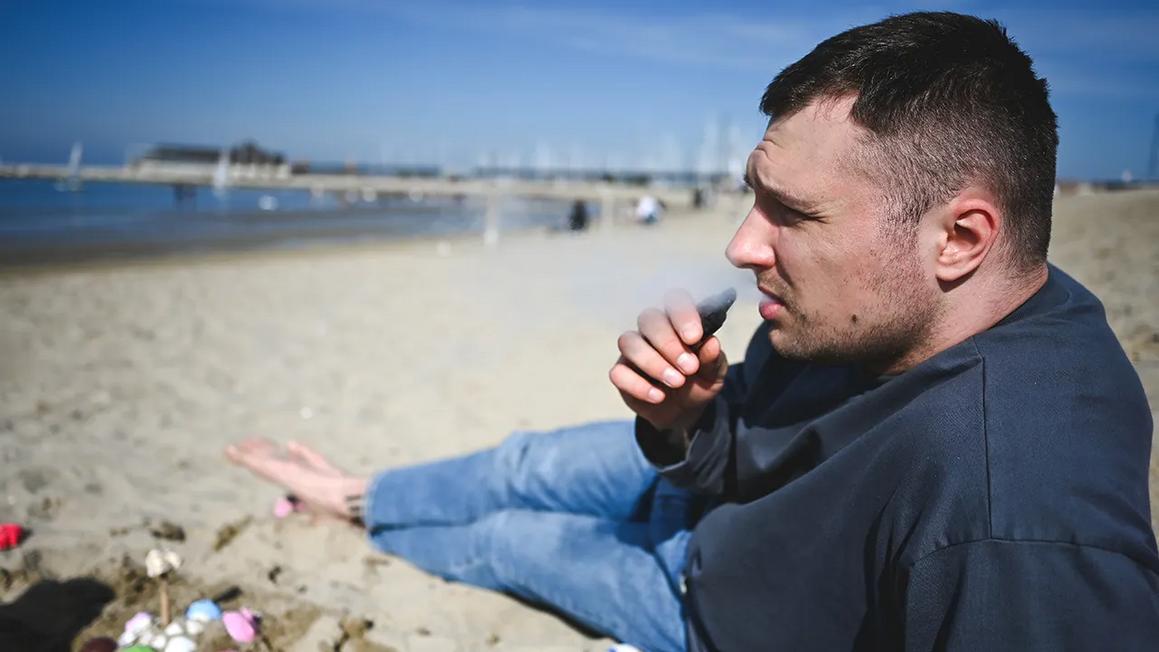 man vaping on beach