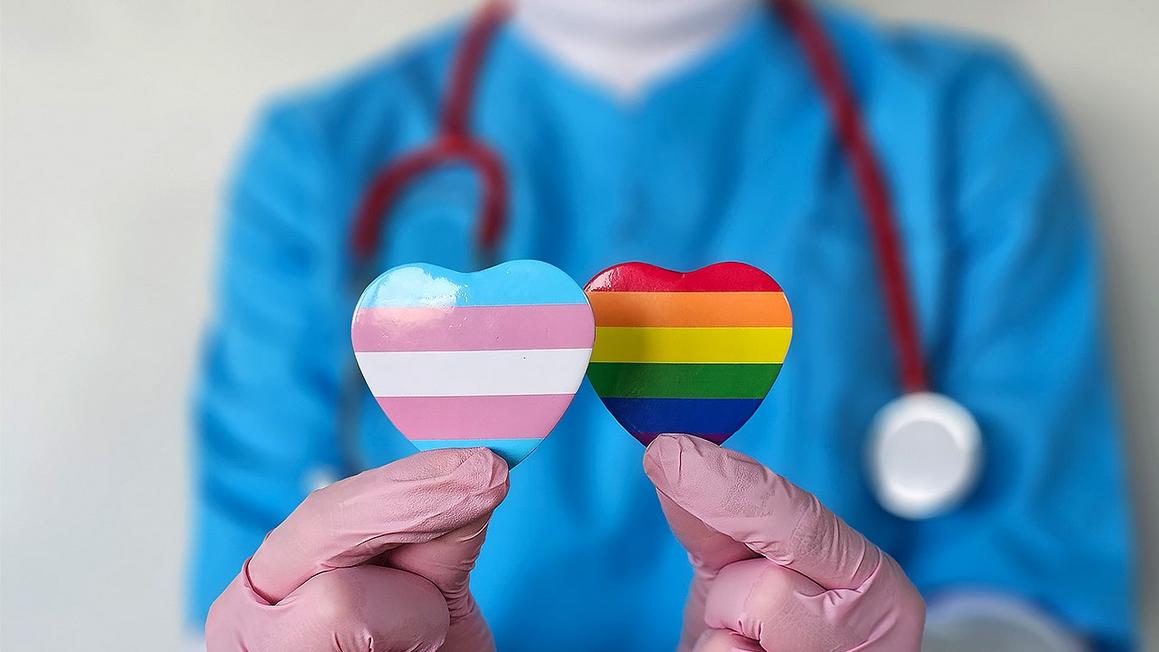 medical worker holding lgbt pins
