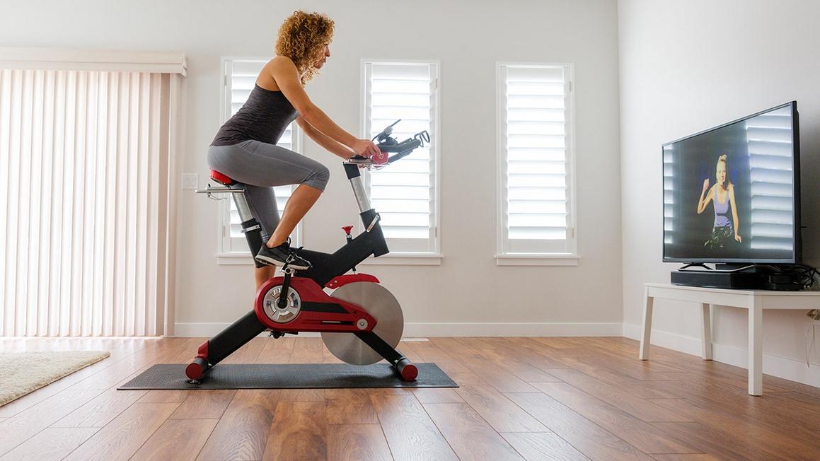 woman cycling at home watching instructor on television