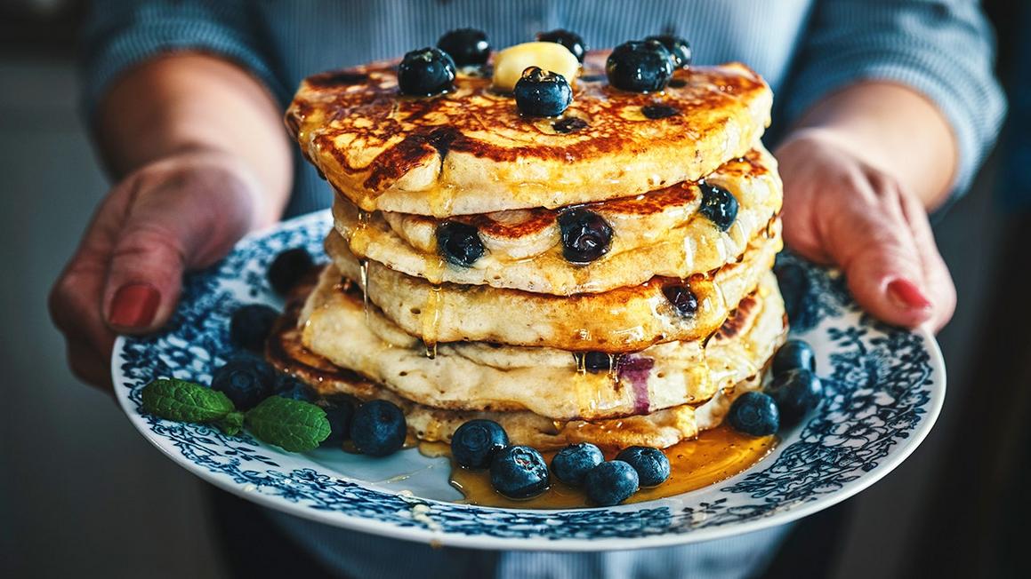 woman holding plate of pancakes