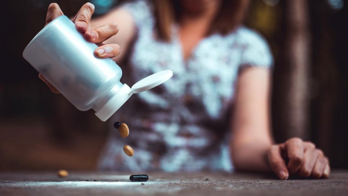 woman pouring out pills